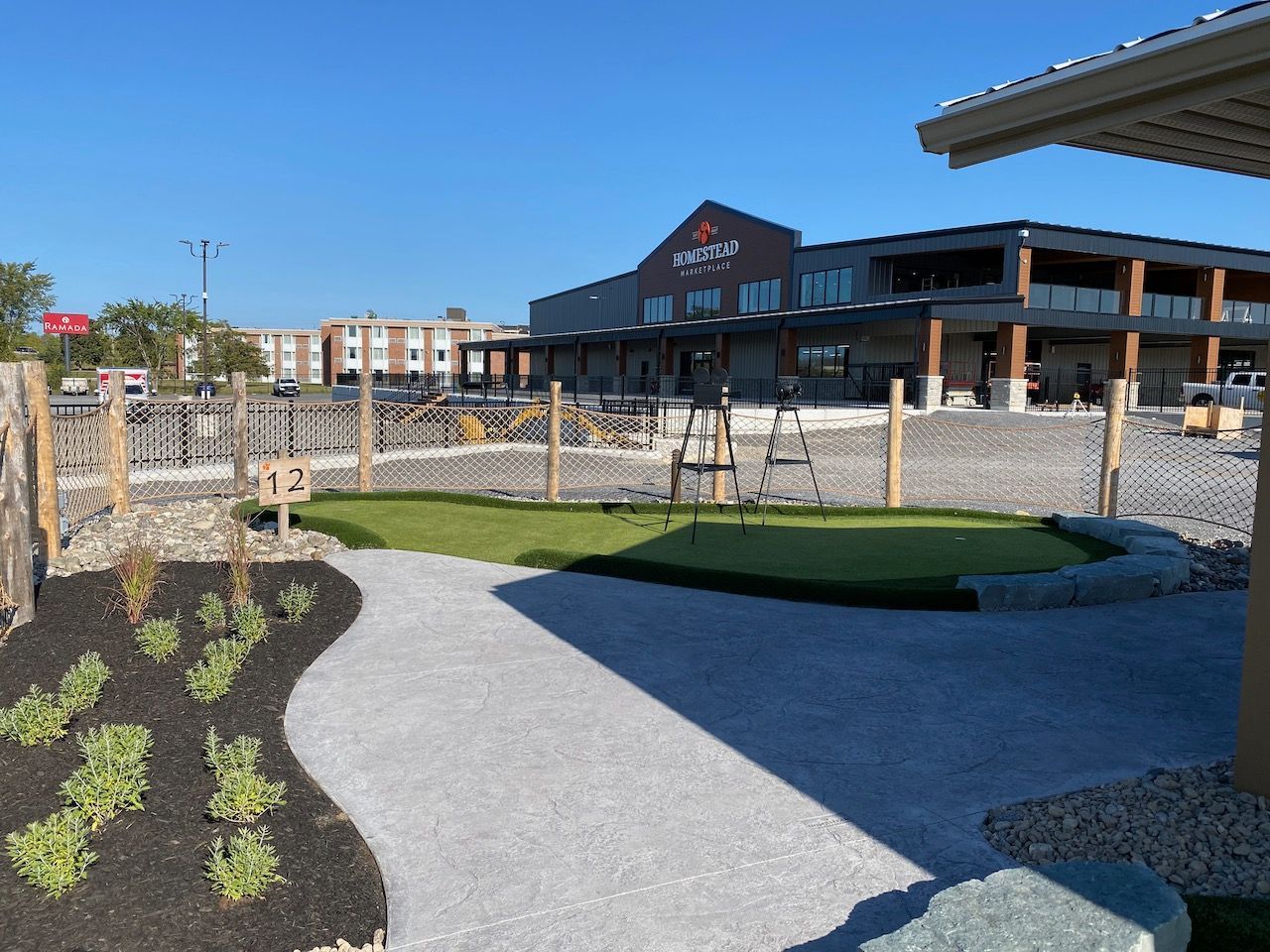 A small putting green is in front of a large building.