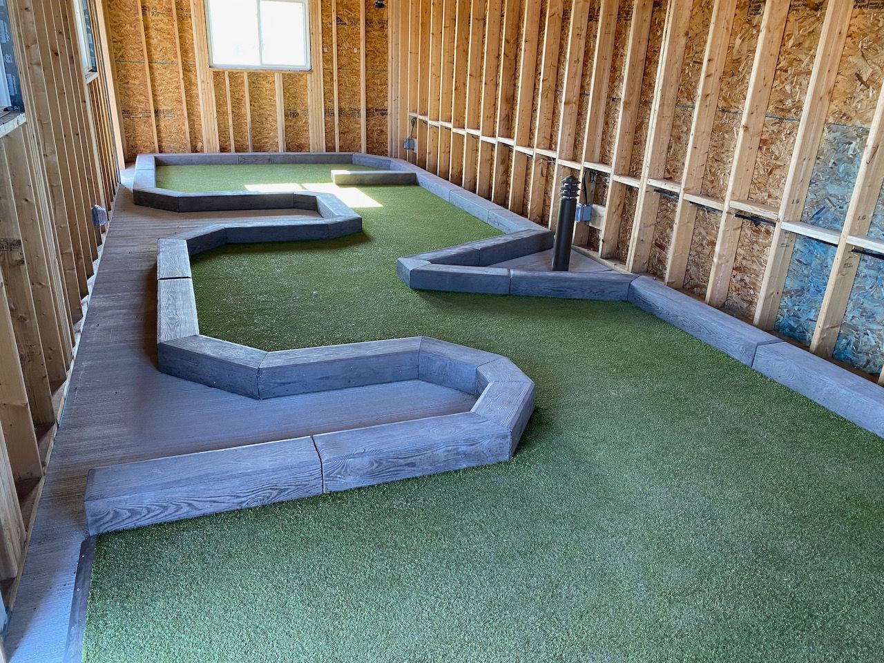 A small golf course is being built in a garage.