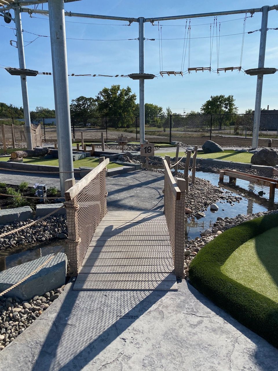 A wooden bridge leading to a golf course in a park.