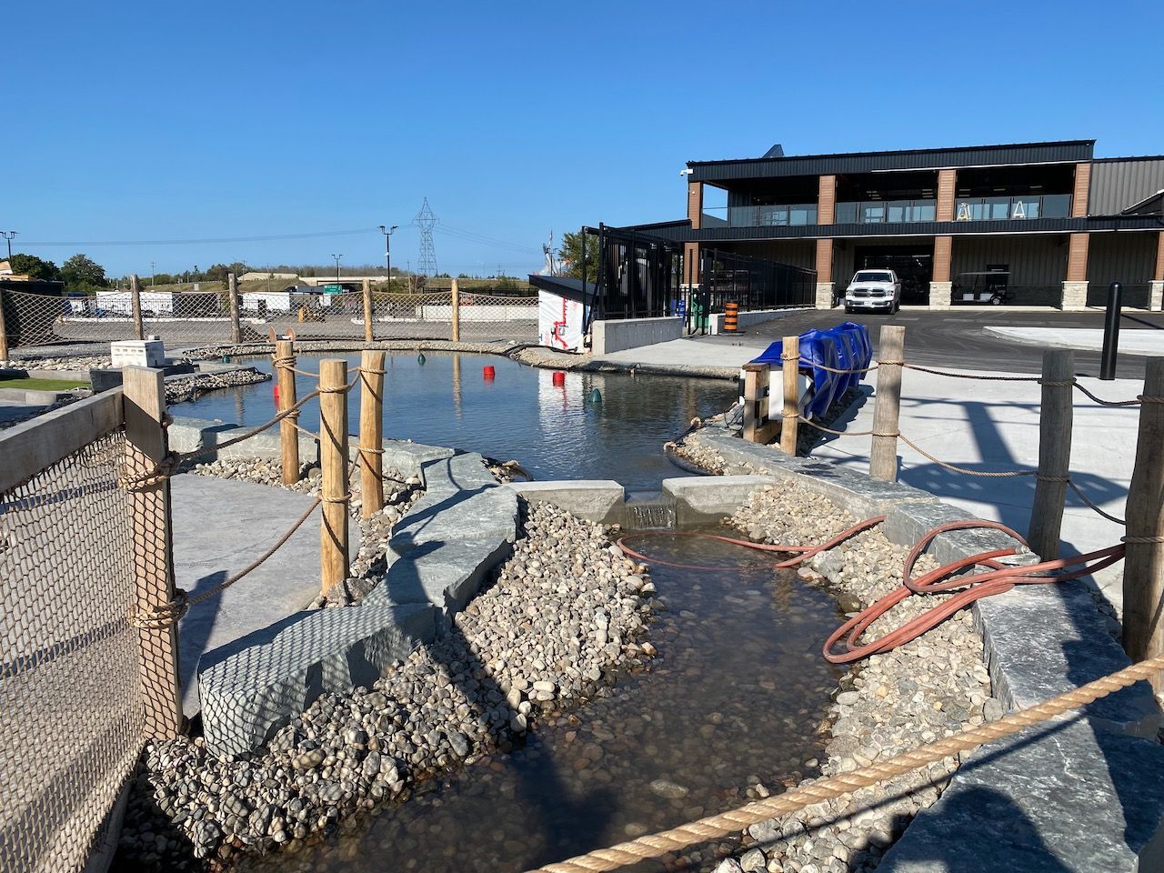 A body of water is surrounded by rocks and a fence.