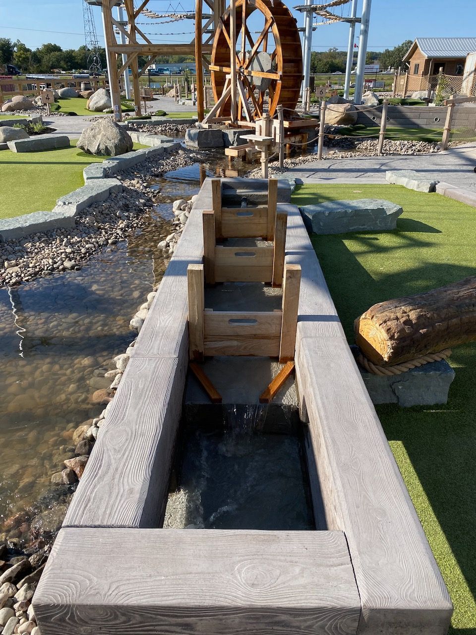 A wooden water wheel is in the middle of a river.