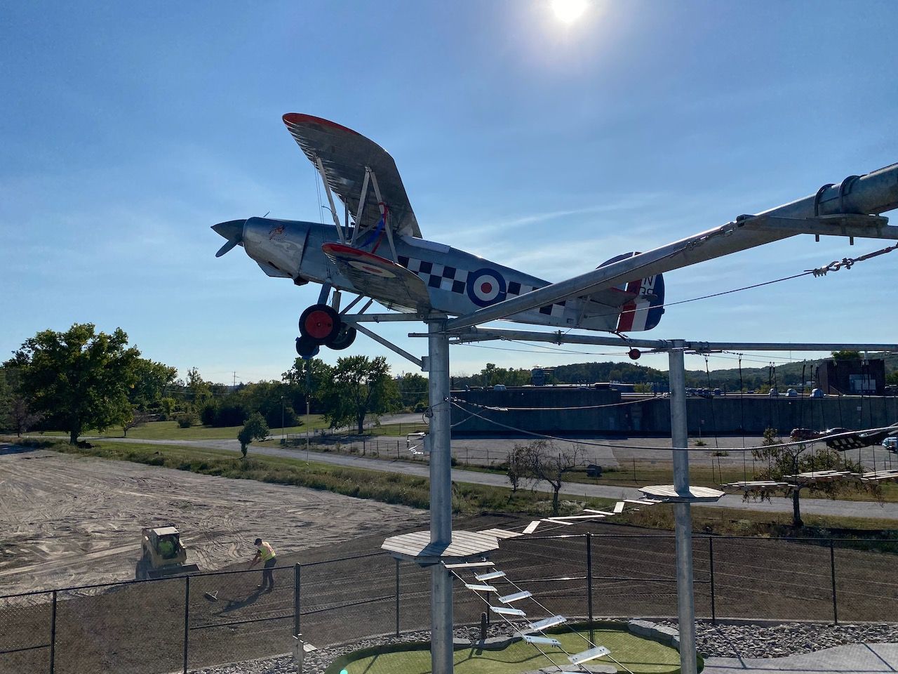 A small plane is sitting on top of a metal pole.
