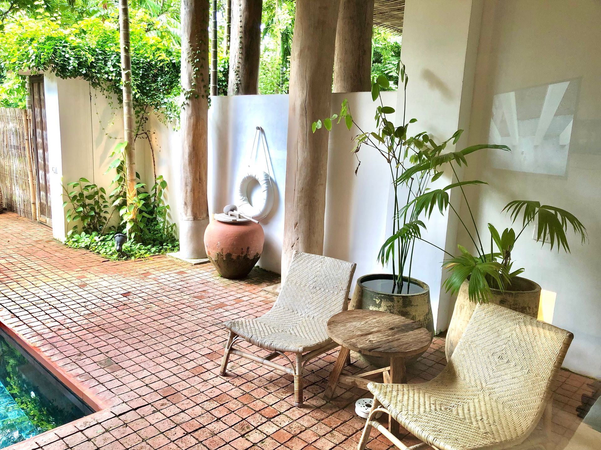 A patio with chairs and a table next to a swimming pool.