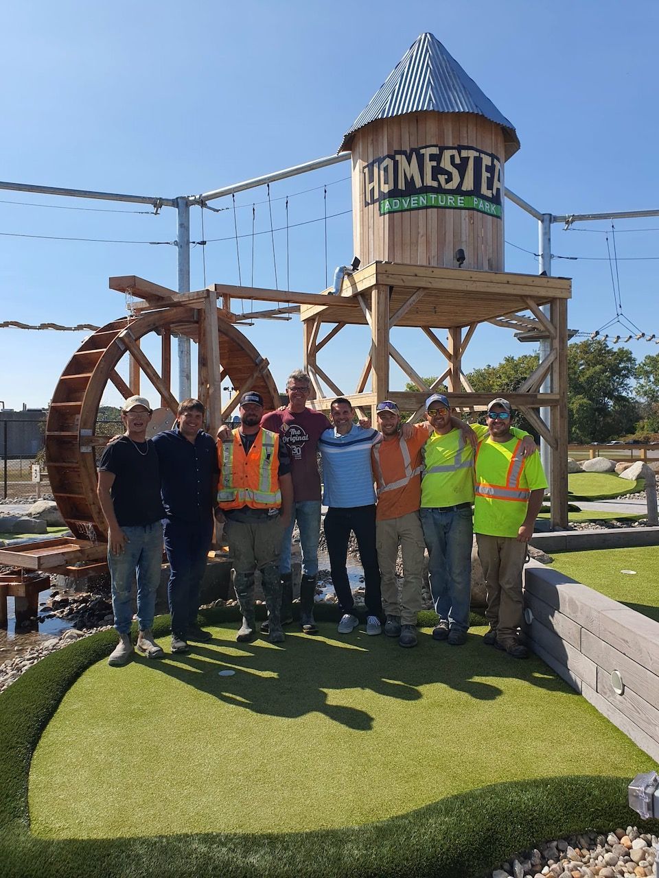 A group of people standing in front of a water tower that says homestead