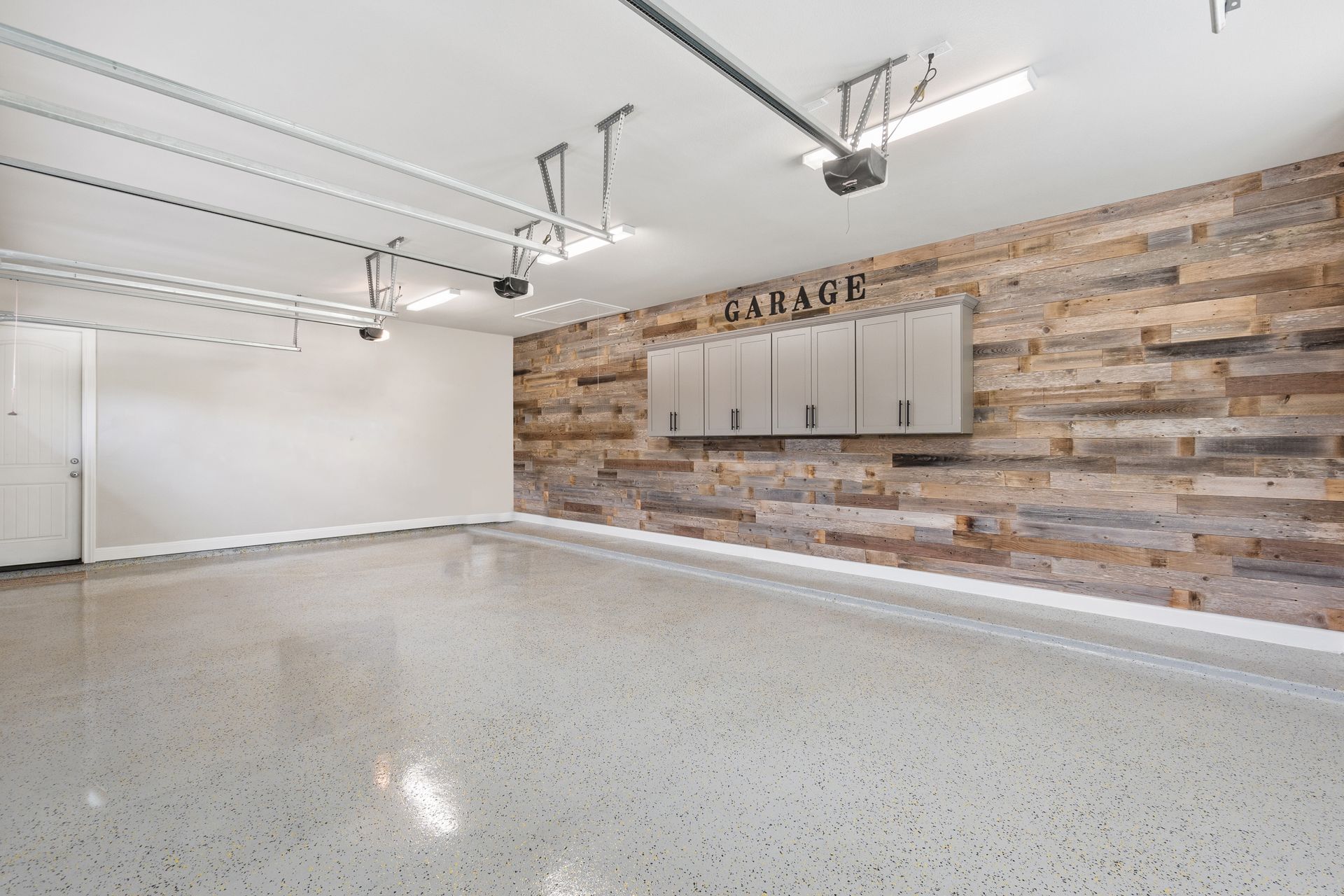 An empty garage with a wooden wall and a concrete floor.