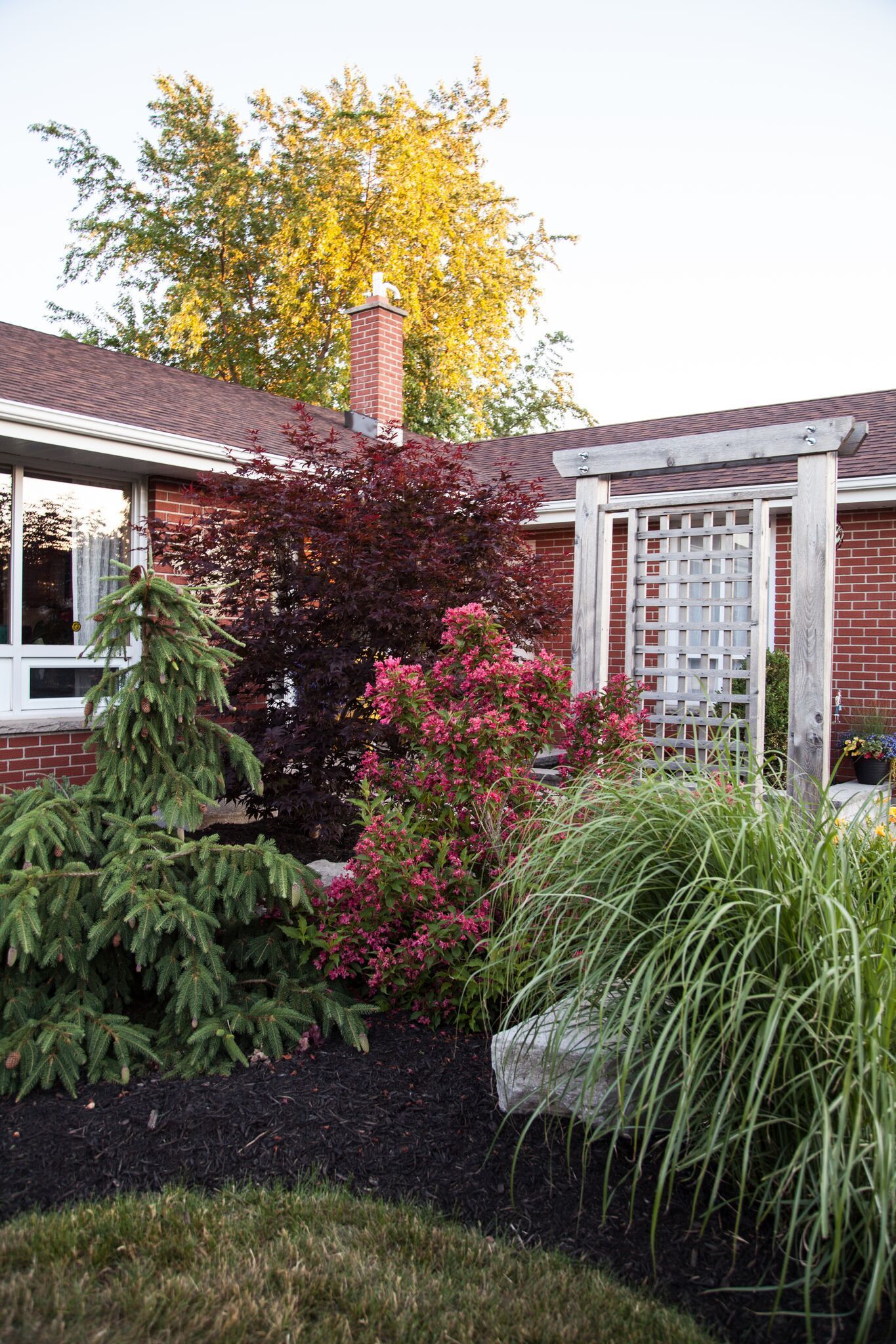 A brick house with a lush green garden in front of it.