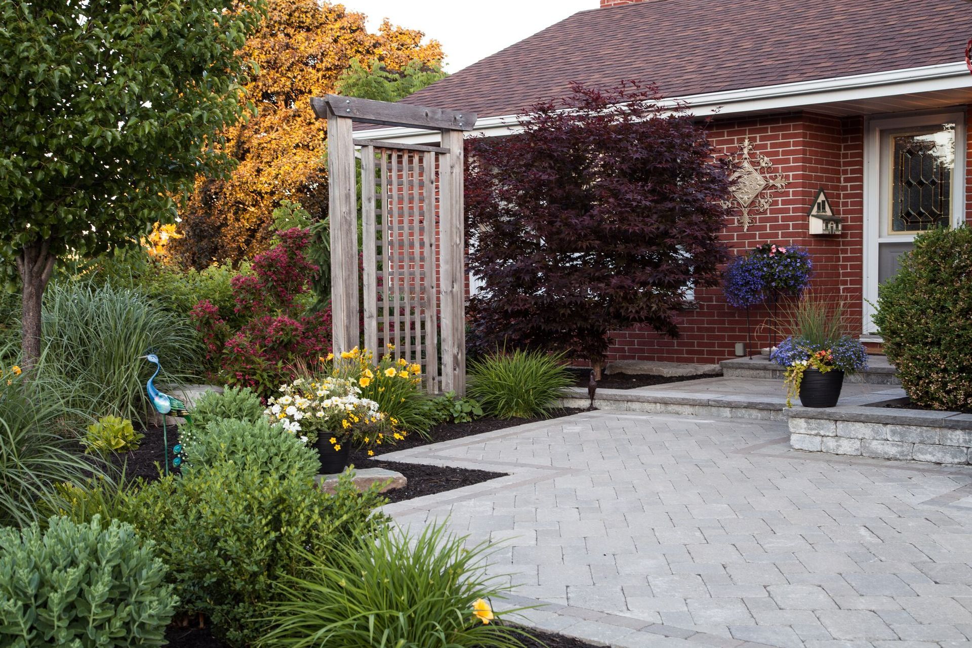 A brick house with a pergola and flowers in front of it