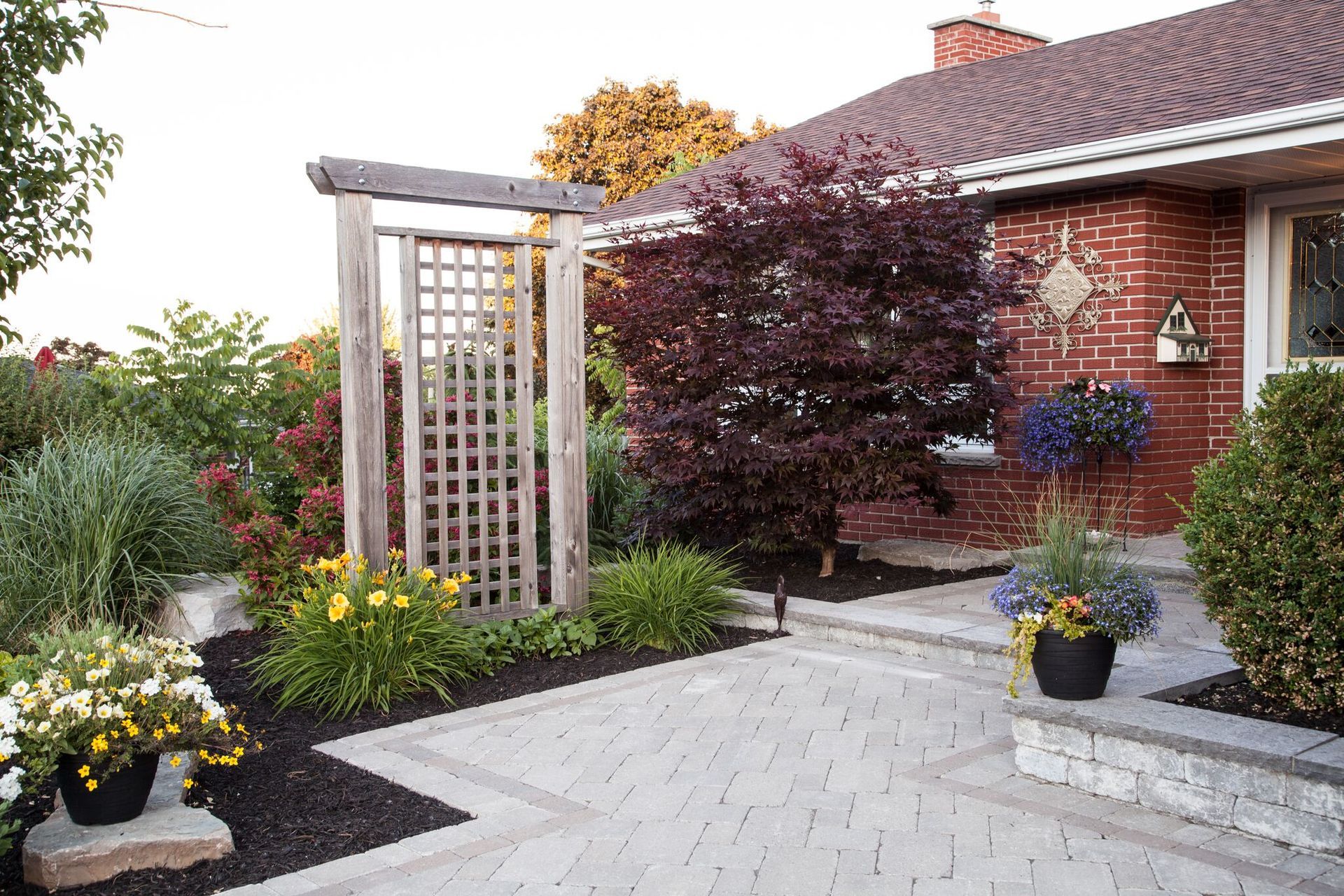 A brick house with a patio and flowers in front of it