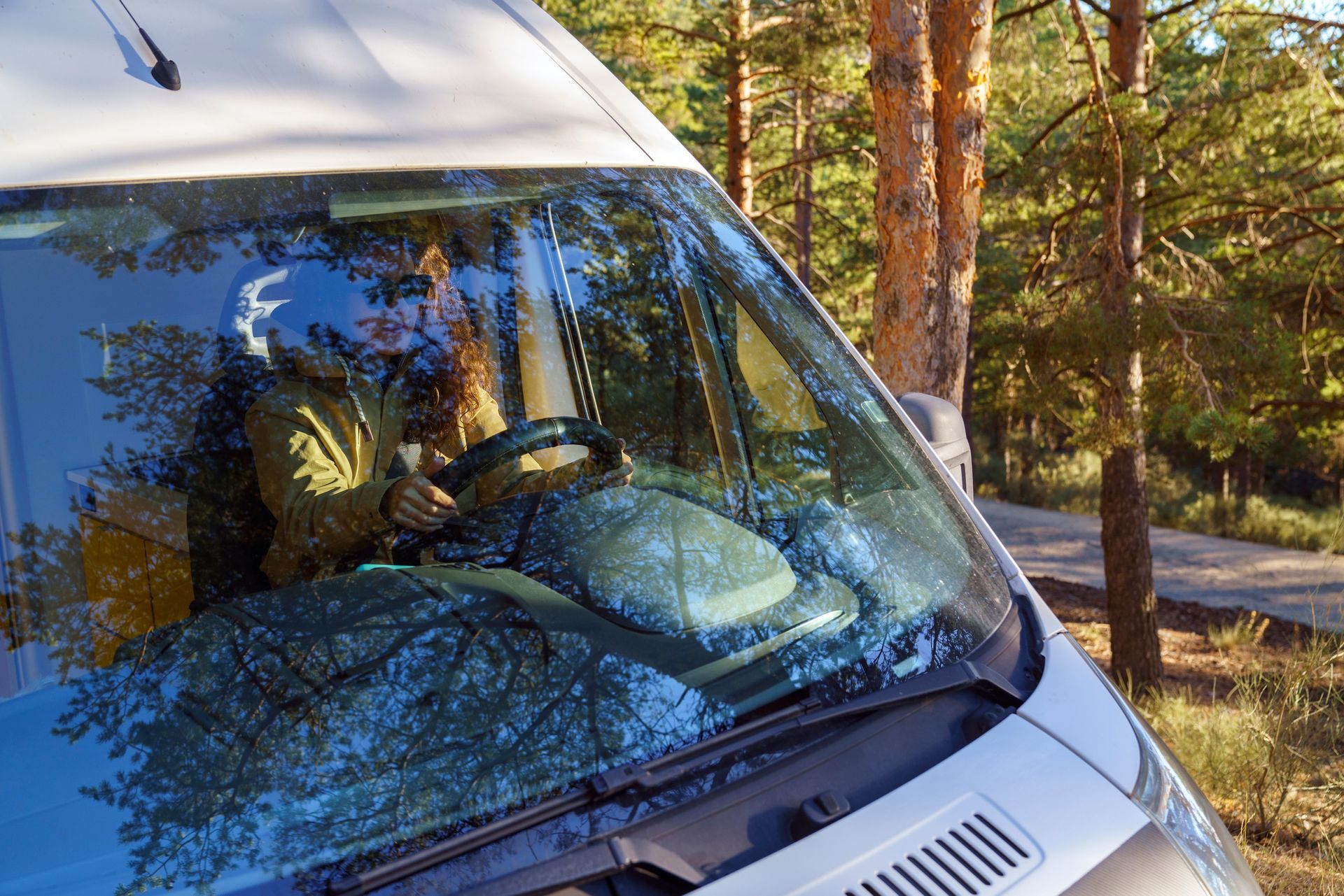 Front view of a woman driving an RV after getting recreational vehicle glass replacement services.