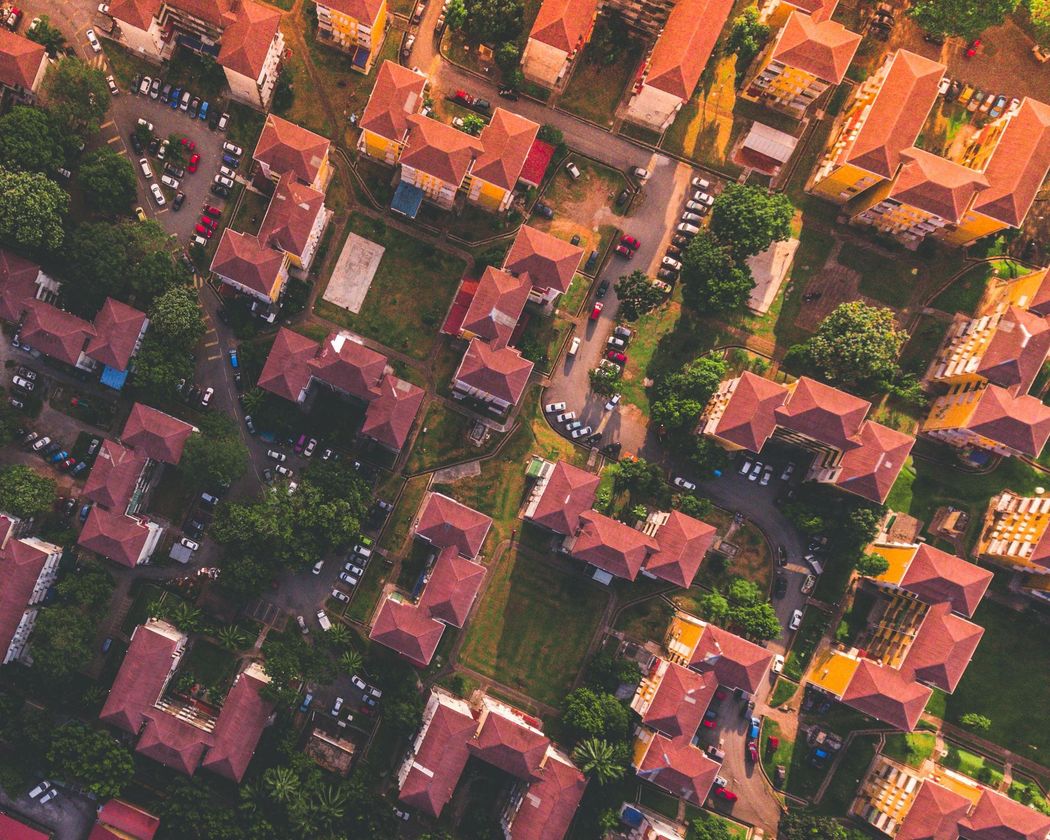 Aerial view of residential buildings with red roofs and green lawns.
