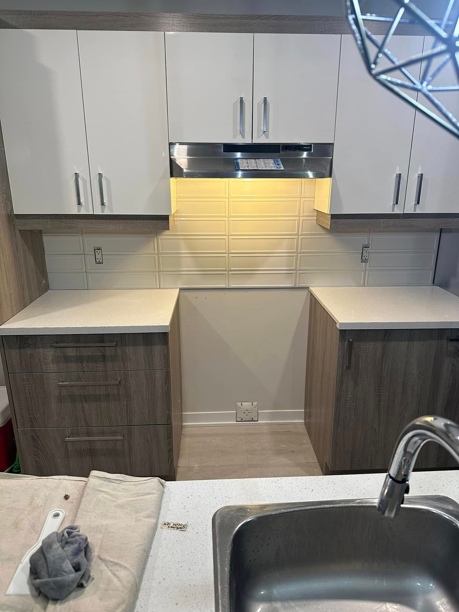 Une cuisine avec des armoires blanches et un évier en acier inoxydable.