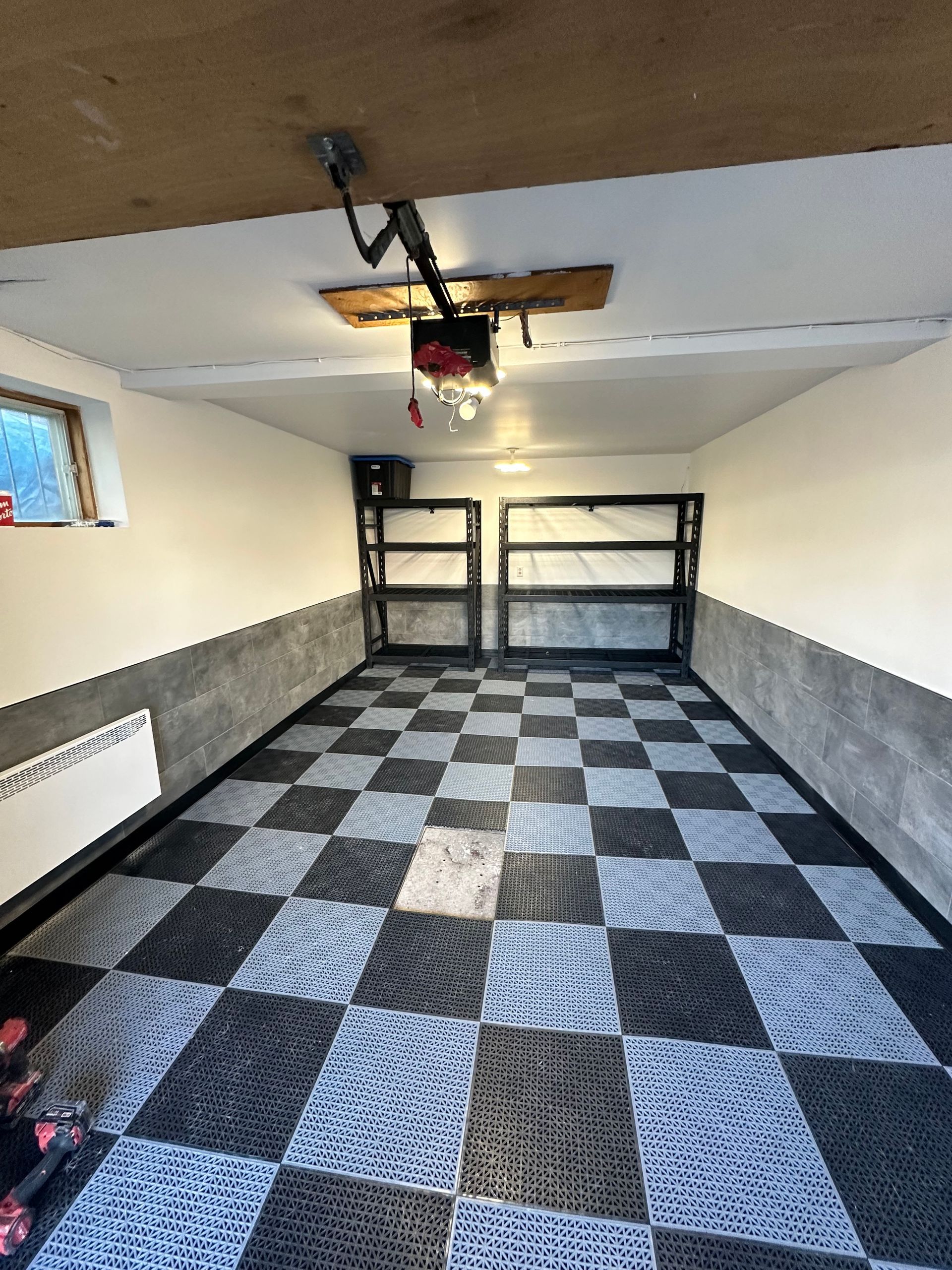 Un garage avec un sol en damier et un ouvre-porte de garage.