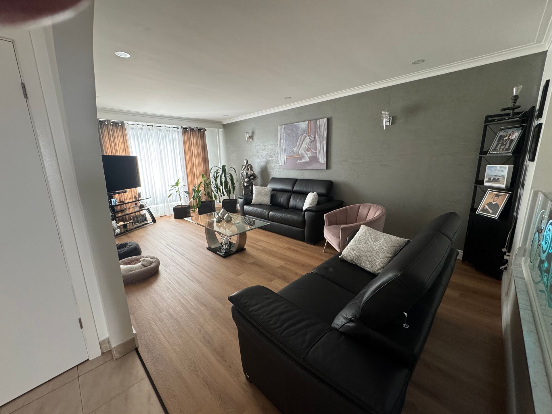 Un salon avec un canapé noir, des chaises et une table basse.