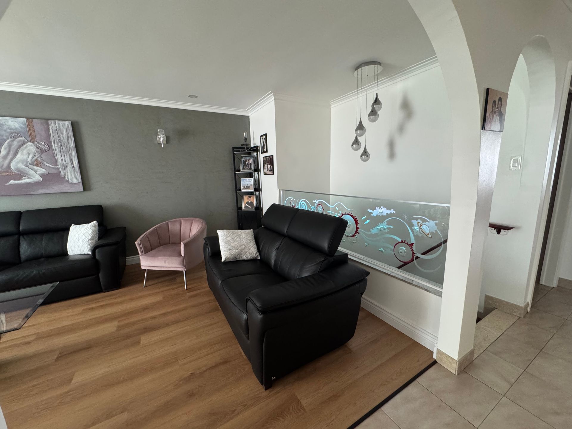 Un salon avec un canapé noir et deux chaises.