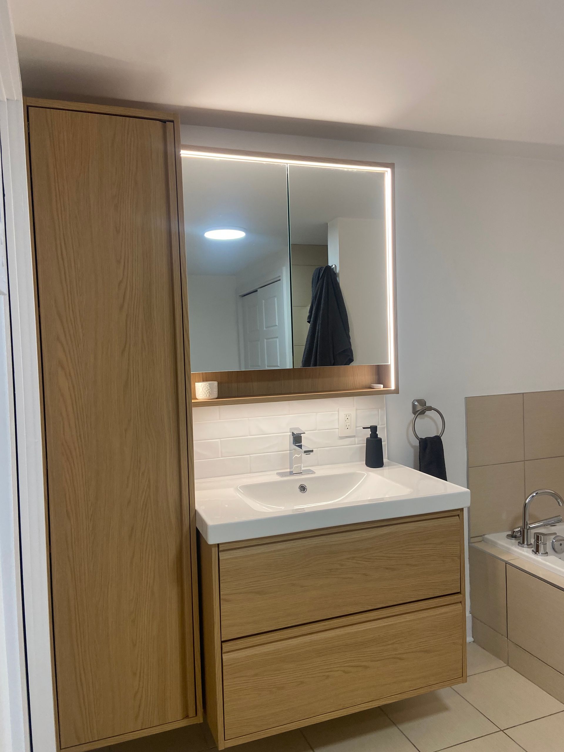 Une salle de bain avec un lavabo, un miroir et des armoires.