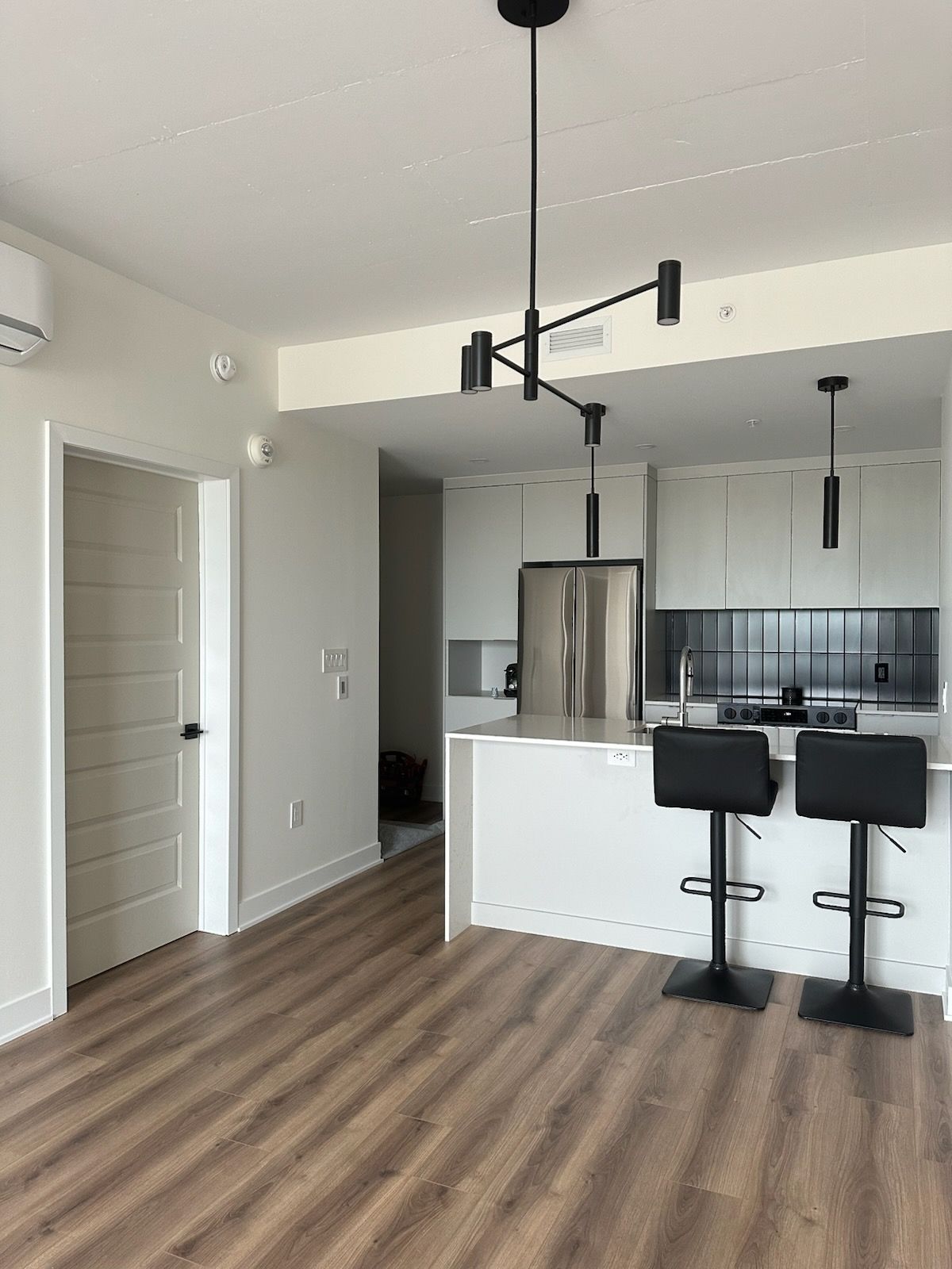 Un salon avec un canapé noir et une table basse en verre