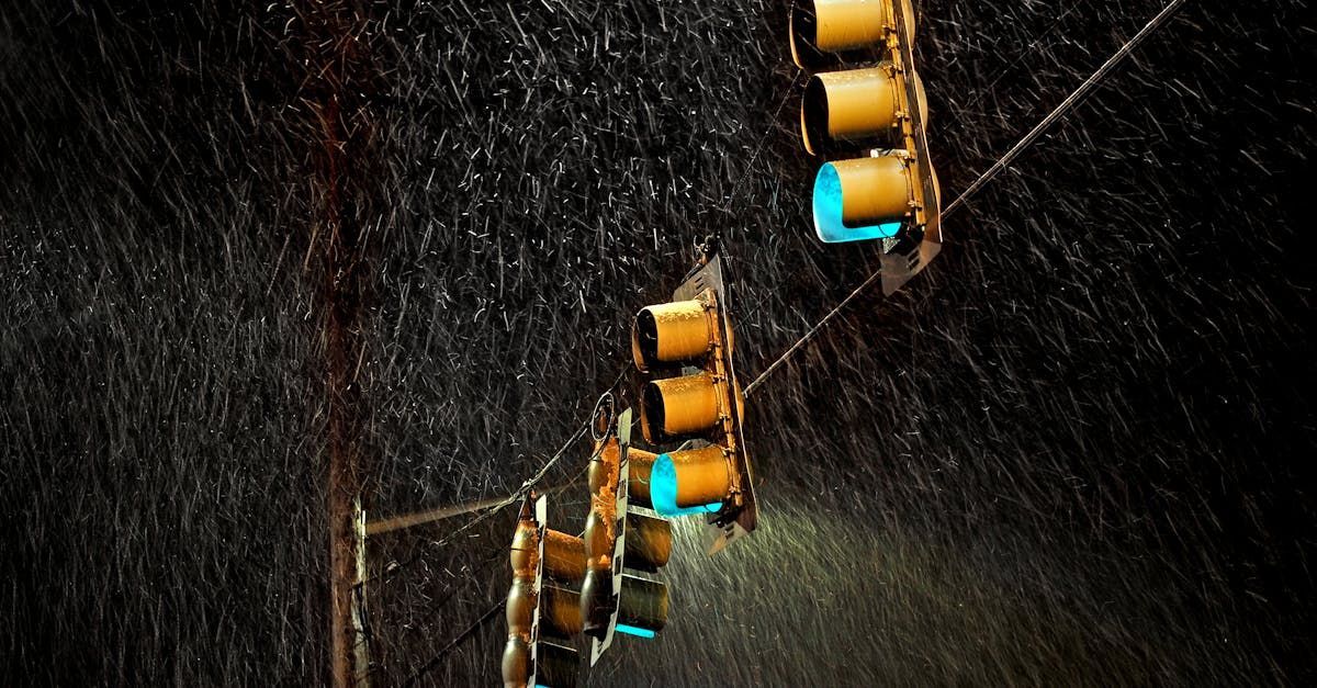 A row of traffic lights are hanging from a pole in the rain.