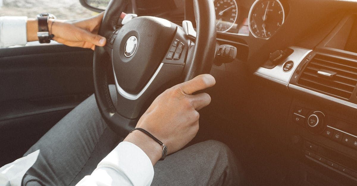 A man is driving a car with his hands on the steering wheel.