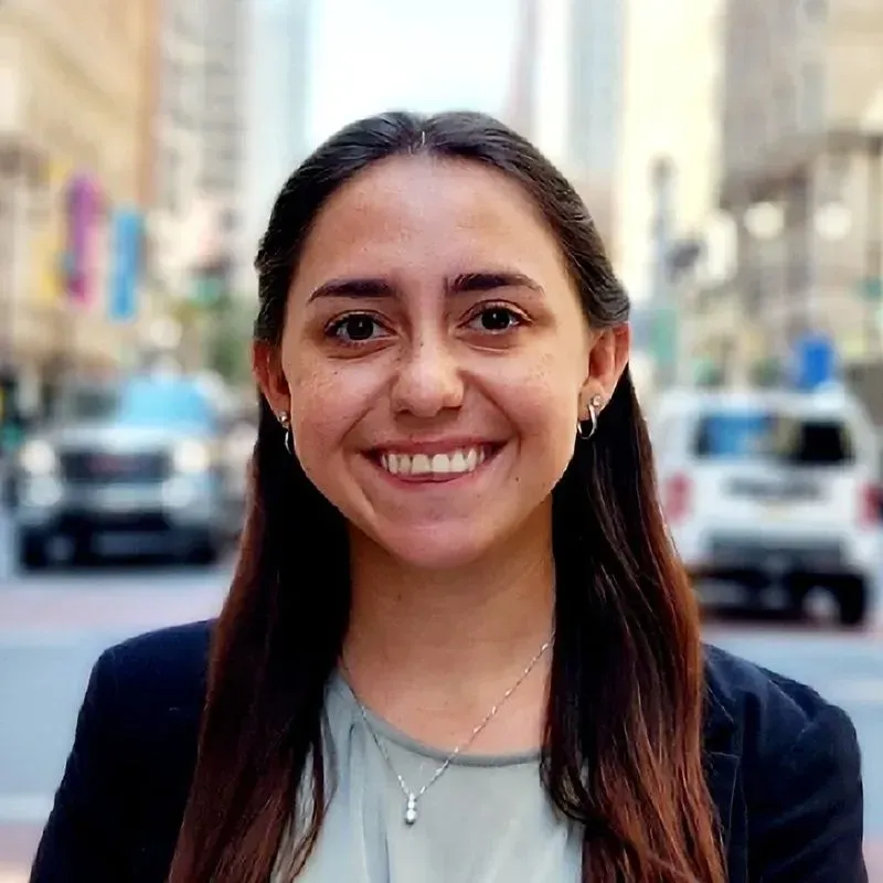 A woman is smiling for the camera in front of a city street.