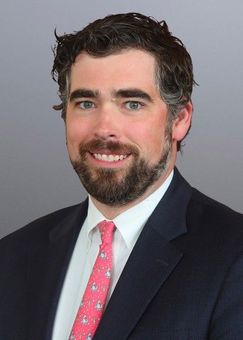 A bald man wearing glasses and a suit and tie is smiling for the camera.