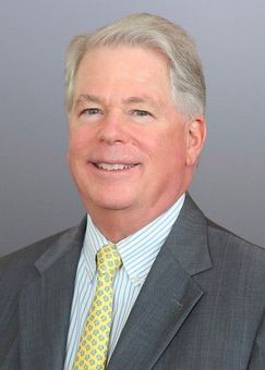 A bald man wearing glasses and a suit and tie is smiling for the camera.