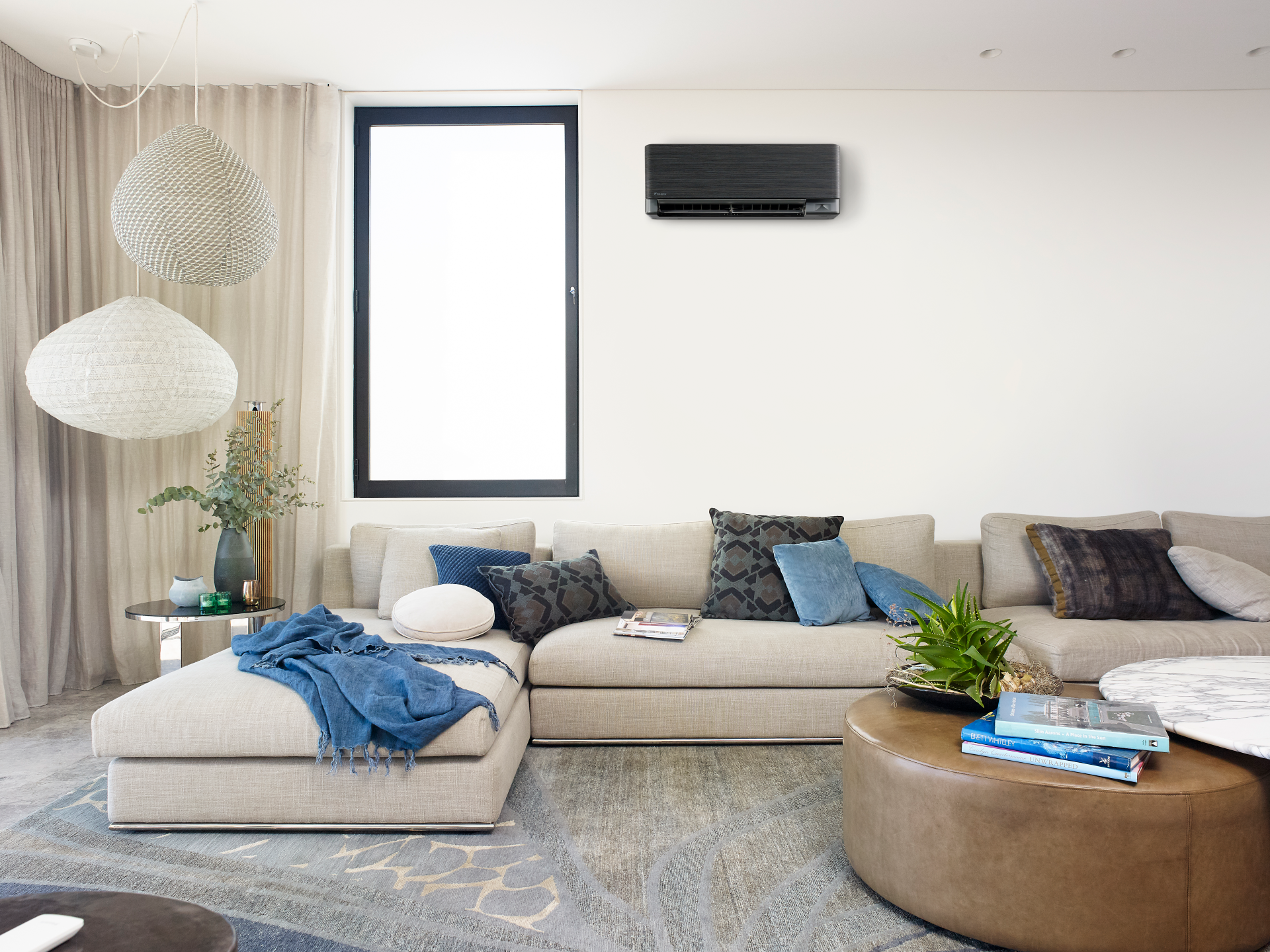 Living room with a sectional sofa, air conditioner, and large window — L & K Electrical & Air Conditioning in Gunnedah, NSW