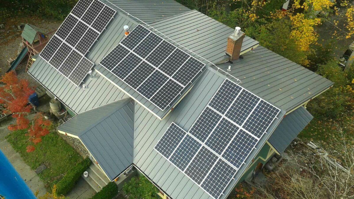 Solar panels installed on a dark grey roof of a house surrounded by trees — L & K Electrical & Air Conditioning in Barraba, NSW