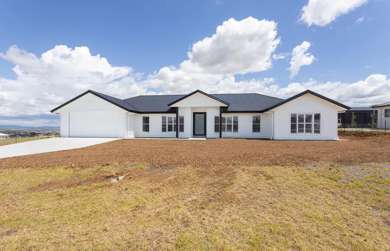 White ranch-style house with black roof and trim on a grassy lot under a blue sky with clouds — L & K Electrical & Air Conditioning in Scone, NSW