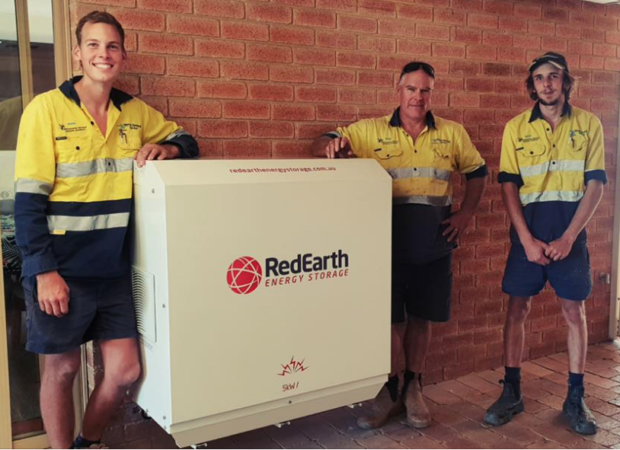 Three workers in uniform stand with a white RedEarth Energy Storage unit against a brick wall — L & K Electrical & Air Conditioning in Scone, NSW