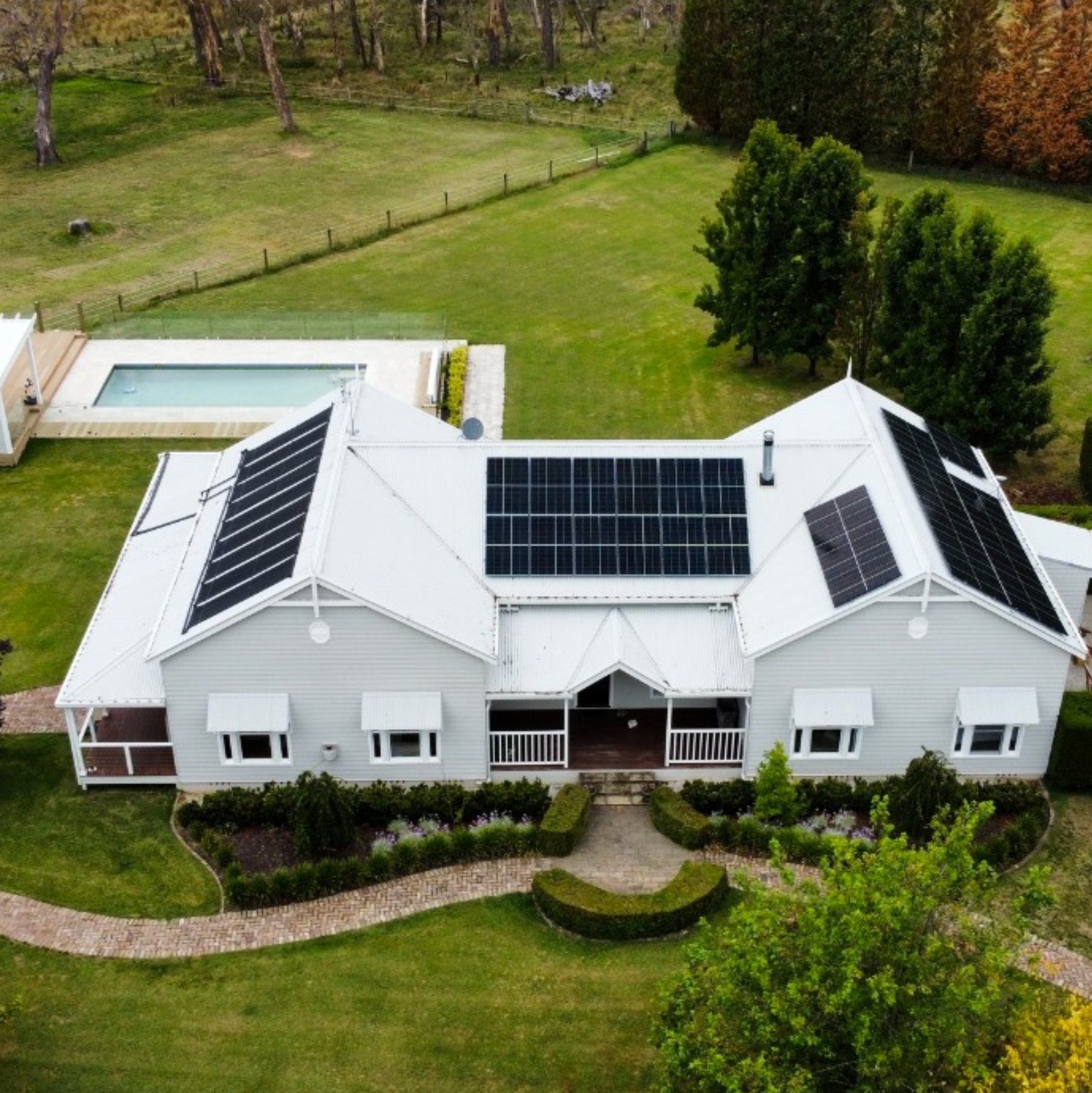 House with solar panels on the roof, a pool, and green lawn — L & K Electrical & Air Conditioning in Scone, NSW