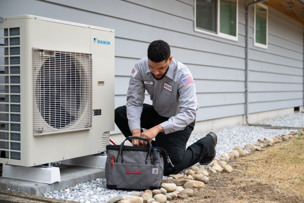 HVAC technician kneels beside an outdoor unit, opening a toolbox near a house — L & K Electrical & Air Conditioning in Tamworth, NSW