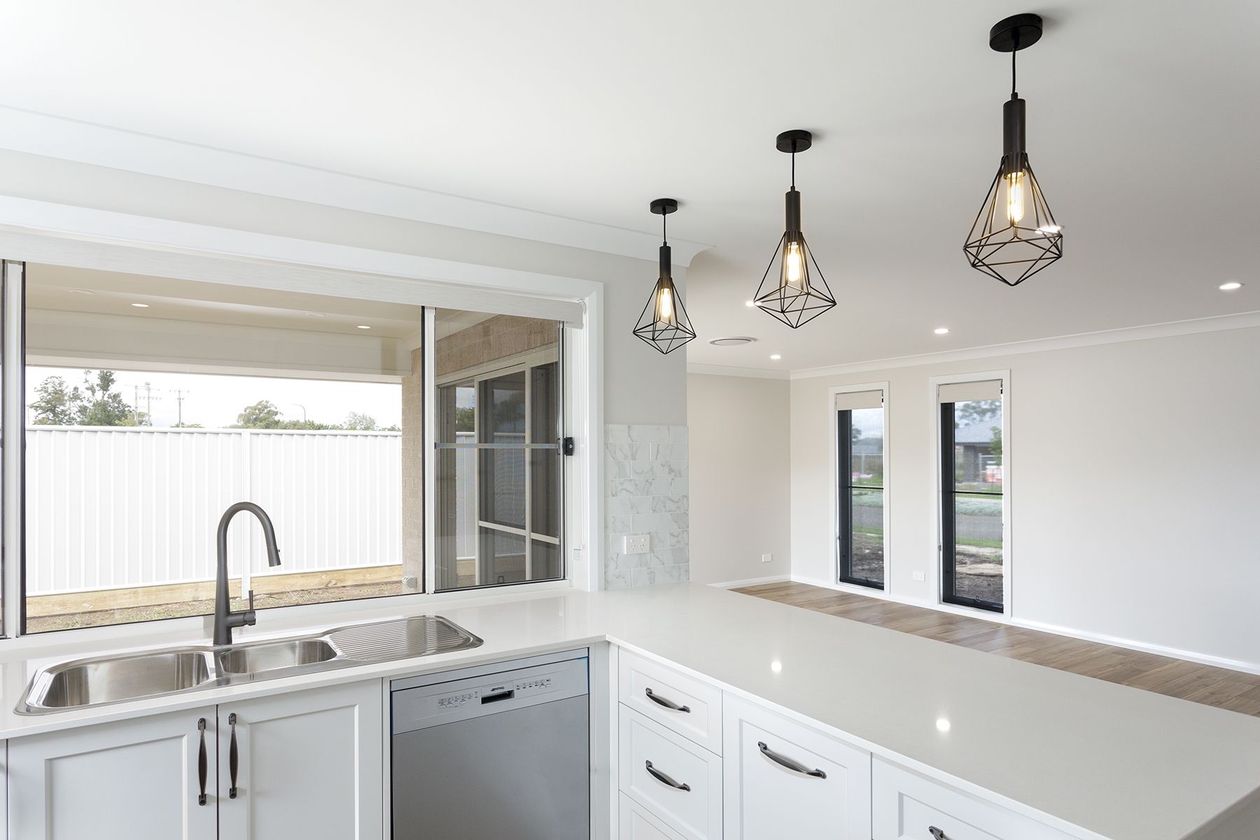 Modern kitchen with white countertops, stainless steel sink, and geometric pendant lights — L & K Electrical & Air Conditioning in Barraba, NSW