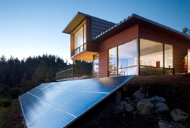 Modern home with large windows and solar panels angled on a hillside — L & K Electrical & Air Conditioning in Tamworth, NSW