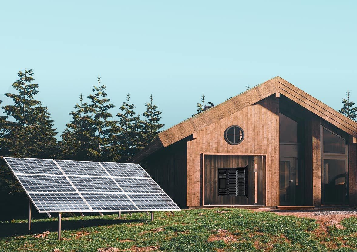 Wooden cabin with solar panels in a green field, trees in the background — L & K Electrical & Air Conditioning in Tamworth, NSW