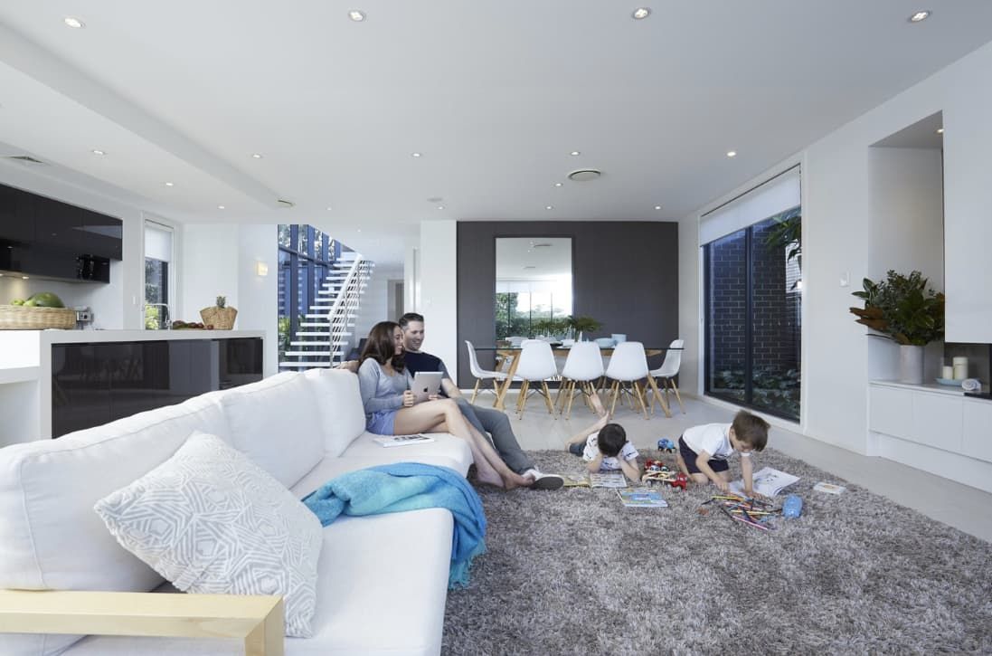 A Family Is Sitting On A Couch In A Living Room — L & K Electrical & Air Conditioning in Tamworth, NSW