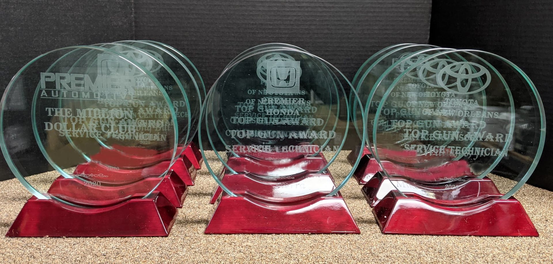 Three glass trophies are sitting on top of a pile of sand.