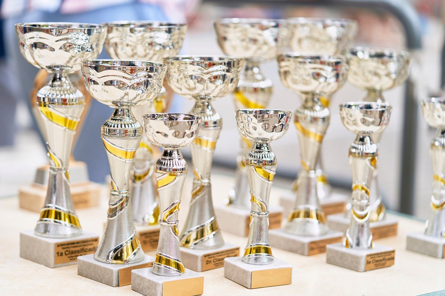 A bunch of silver and gold trophies are sitting on a table.