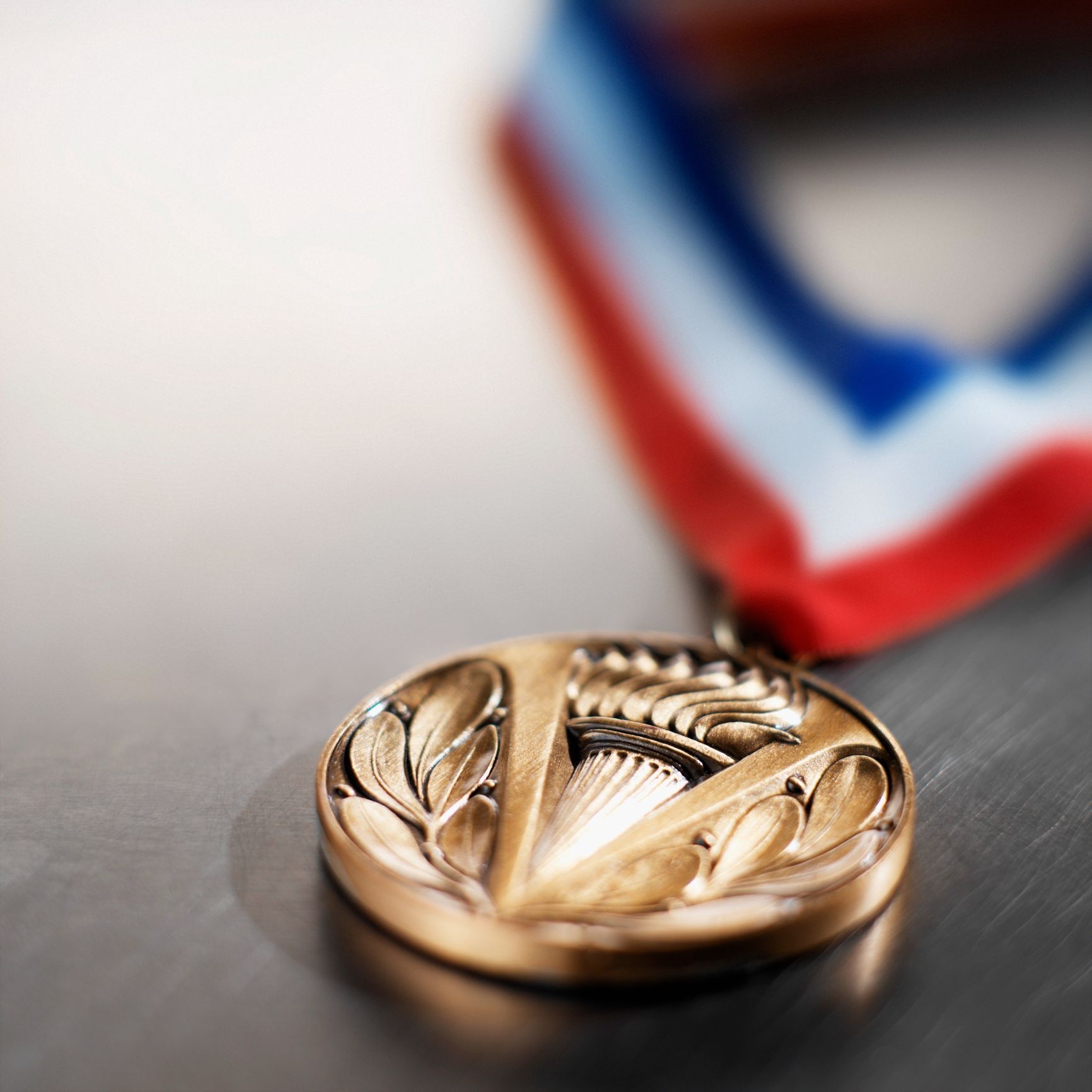 A gold medal with a red white and blue ribbon around it