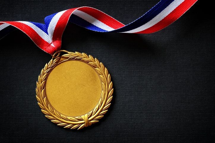 A gold medal with a red white and blue ribbon around it