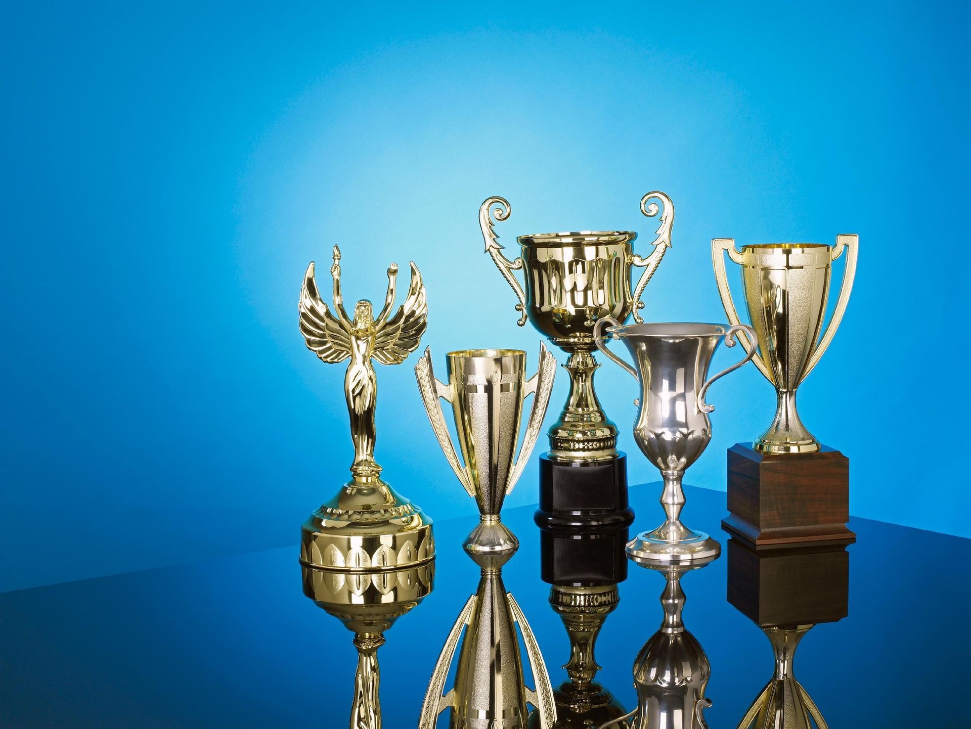 A group of gold trophies on a table with a blue background