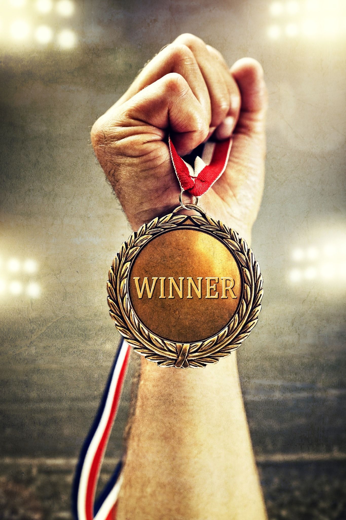 A person is holding a gold medal with the word winner on it.
