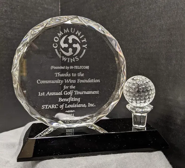 A glass trophy with a golf ball on top of it