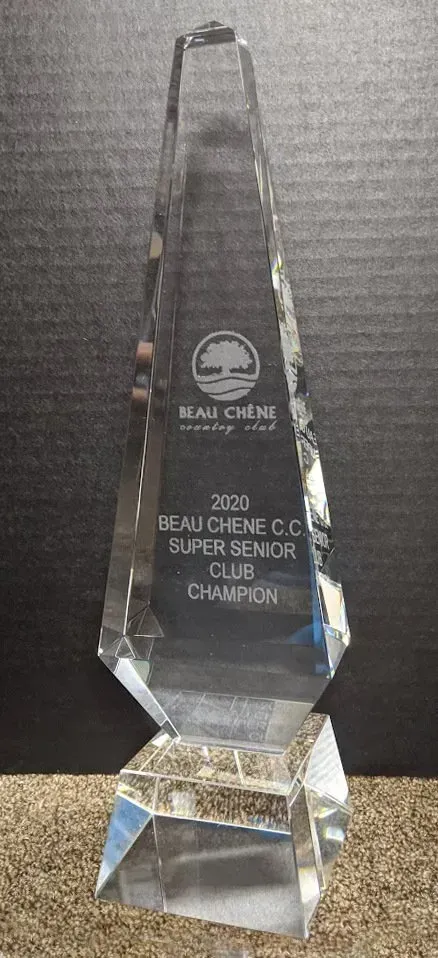 A clear glass trophy is sitting on top of a wooden table.