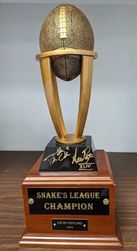 A snake 's league champion trophy is sitting on a wooden table.