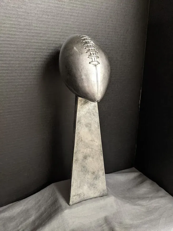 A silver football trophy is sitting on top of a table.