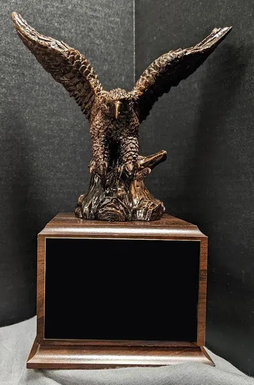 A statue of an eagle sitting on top of a wooden plaque