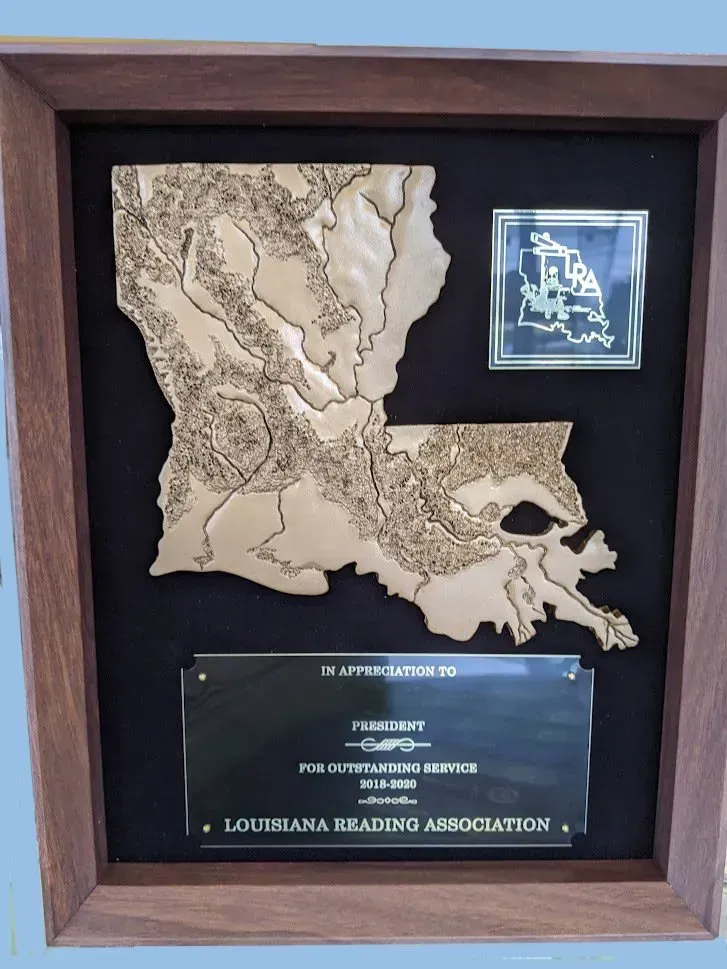 A wooden map of louisiana is in a wooden frame