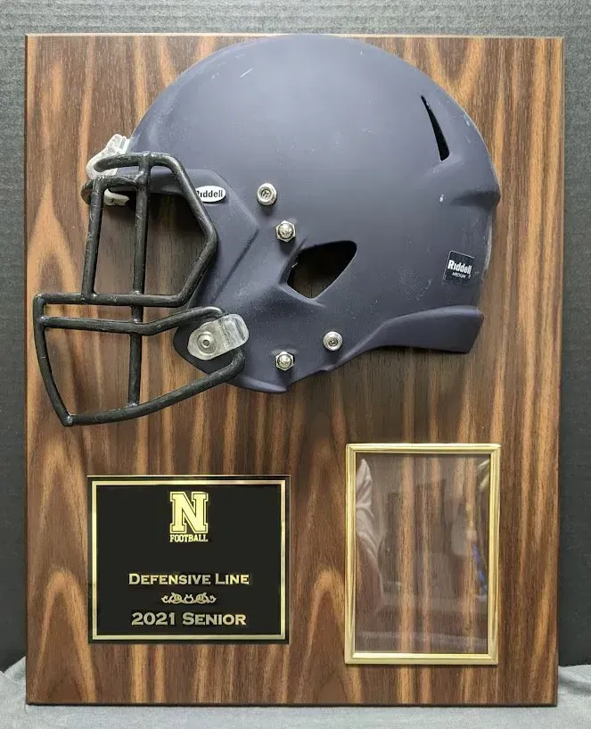 A football helmet is displayed on a wooden plaque