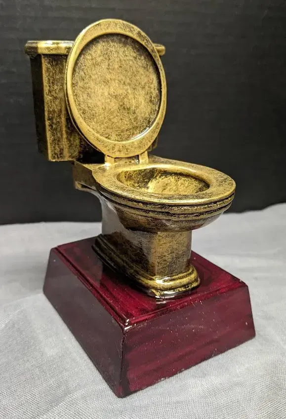 A statue of a toilet on a wooden base.