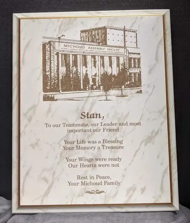 A framed picture of a building with the name stan on it